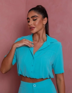 Detail of teal short sleeve crop shirt with button-down collar and elastic waistband