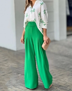 Detail von grüner High-Waist-Hose mit weitem Bein und einer geblümten weißen Bluse