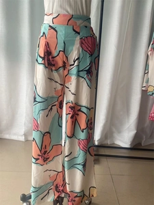 Detail of high waisted wide leg pants with colorful floral print in chiffon fabric