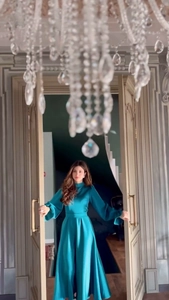 Détail d'une robe longue en soie vert foncé avec volants élégants et manches longues