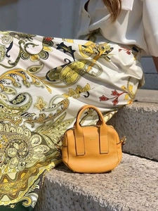 Sac à main élégant en cuir jaune sur marche en pierre avec robe à imprimé floral en fond
