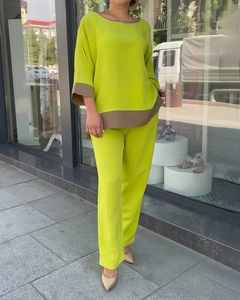 Detail of neon green loose fit two-piece set with brown trim contrast and straight pants