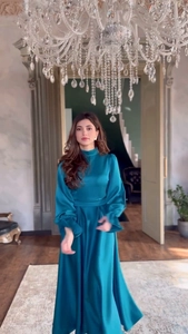 Détail macro d'une robe longue en satin bleu paon avec col montant et taille plissée