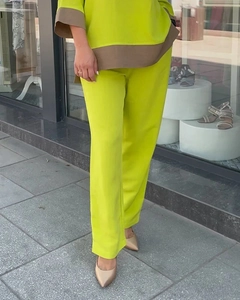 Detail of lime green two-piece set featuring contrast brown trim on sleeves and hemline