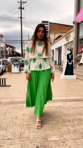 Detail of white daisy print long sleeve top and green pleated midi skirt for women