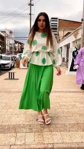 Outdoor street style shot of a white floral long sleeve top and green pleated maxi skirt