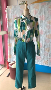 Detailed view of long sleeve shirt with abstract artistic print and peacock blue trousers