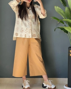 Detail of linen shirt with botanical prints and yellow wide-leg trousers ensemble