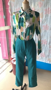 Detail view of printed long sleeve shirt with dark green high waist trousers for women
