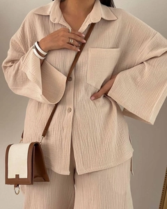 Detailed texture of beige pleated fabric on casual long sleeve shirt and wide leg pants