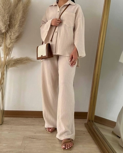 Detailed texture of beige pleated fabric on loose-fit shirt and wide-leg trousers set