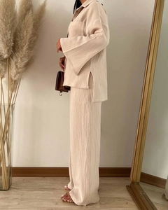 Detail of beige crinkled fabric texture on long sleeve shirt and wide leg trousers set