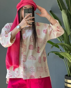 Detail of plus size cotton linen shirt with red tree prints and matching pink trousers