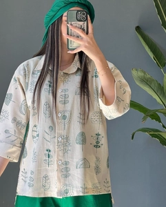 Detail of linen-cotton fabric shirt featuring dark green botanical prints and buttons