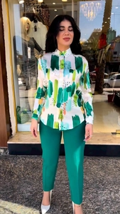 Detail of printed white shirt with artistic strokes paired with dark green straight trousers