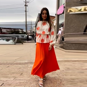 Women's chic two-piece set featuring a floral long-sleeve top and orange pleated maxi skirt