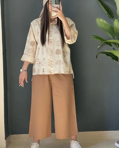 Close-up of beige cotton linen shirt with tree prints and matching brown wide-leg pants