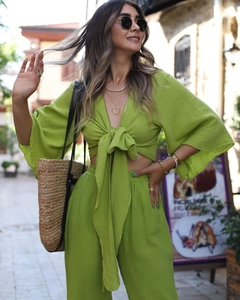 Detail of green bell sleeve tie-up crop top and high-waisted wide-leg trousers