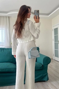 Detail of white pleated long sleeve crop top and high waist wide leg pants set