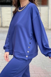 Detail of navy blue tracksuit showing decorative silver metal buttons on the side seam