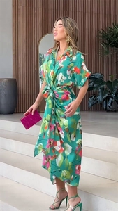 Detail of green floral loose dress with V-neck and vibrant orange and pink patterns