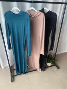 Close-up of three long-sleeved hooded dresses in dark green, dusty pink, and black colors