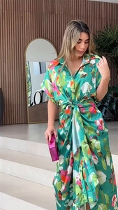 Detail view of tropical floral print on green satin dress with waist tie and buttons