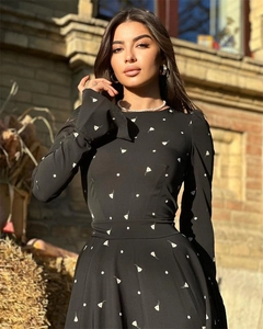 Dettaglio di un elegante abito lungo nero a maniche lunghe con stampa floreale e laccio