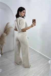 Detail view of beige linen-blend crop top back button and high-waisted wide-leg trousers