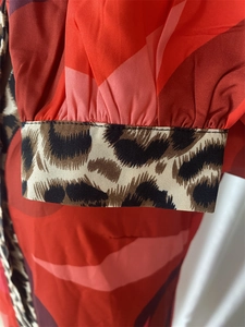 Détail de la manche à motif géométrique rouge avec poignet léopard et couture de précision