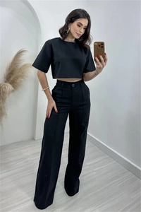 Detail of minimalist black two-piece set featuring high-waisted wide-leg trousers and crop top