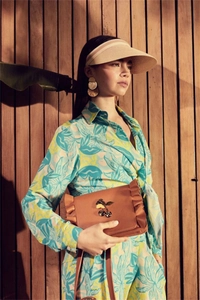 Detail of brown ruffle handbag with cherry jewel and tropical leaf print garment