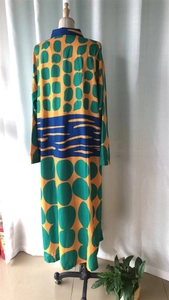 Detail of loose printed maxi dress with ginger yellow base and green polka dot patterns