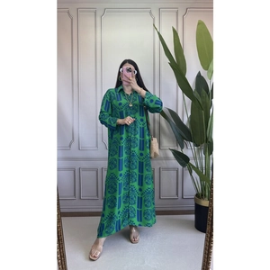 Dettaglio di un abito verde a maniche lunghe con motivi etnici e elegante collo a revers