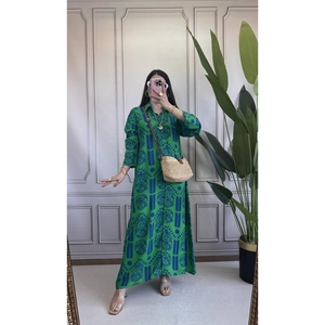 Dettaglio di un abito lungo verde con motivi vintage blu e colletto con bottoni