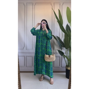 Dettaglio di un abito lungo verde smeraldo con motivi etnici blu scuro e revers