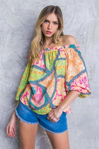 Dettaglio del top con spalle scoperte, stampa paisley e frange degli shorts in denim