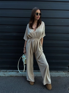 Detail of champagne satin jumpsuit featuring a deep V-neck and high-waist belt tie