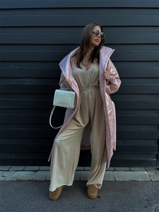 Detail of a beige V-neck wide-leg jumpsuit paired with a pink quilted coat in a street style look