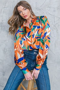 Detail of long sleeve blouse with vibrant tropical leaf print and button-up collar design