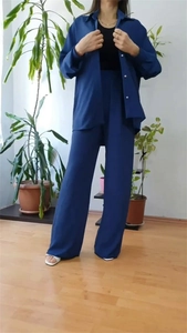 Detail of dark blue high-waisted wide-leg trousers and shirt with silver button accents