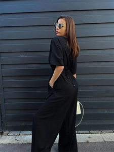 Detail of a black jumpsuit featuring adjustable waist drawstring with metallic bead accents