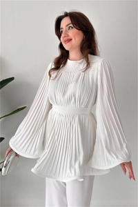 Detailed view of the fine pleats and flared cuffs on a white long-sleeve blouse