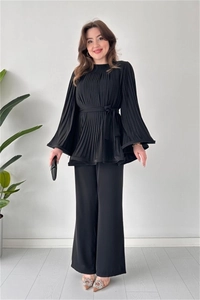 Close-up of elegant black pleated fabric and waist tie detail on a two-piece set