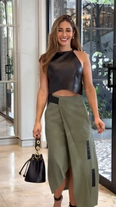 Détail d'un haut licou noir et d'une jupe portefeuille olive avec un sac seau à cordon noir