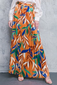 Detail of a pleated maxi skirt with orange tropical leaf print and fine accordion pleats