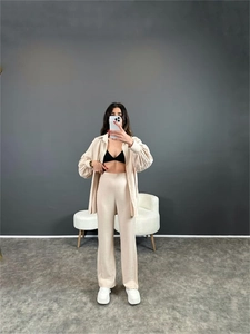 Détail d'une chemise ample beige à manches longues et d'un pantalon large texturé