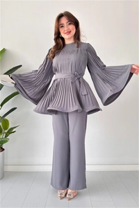 Detail of high-density pleated gray two-piece set featuring flared sleeves and waist tie