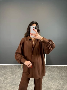Détail de la texture plissée marron foncé sur l'ensemble chemise ample et pantalon