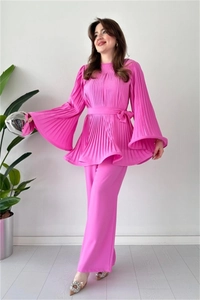 Detail of bright pink pleated two-piece set featuring flared sleeves and waist tie